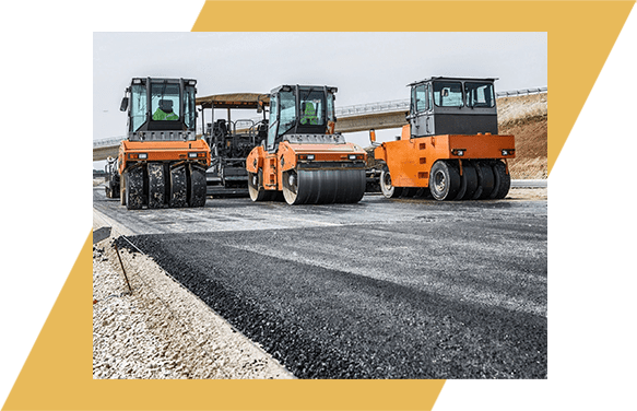 A group of construction vehicles parked on the side of a road.