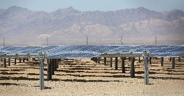 A large field of solar panels in the desert.