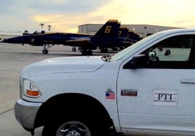 A white truck parked in front of an airplane.