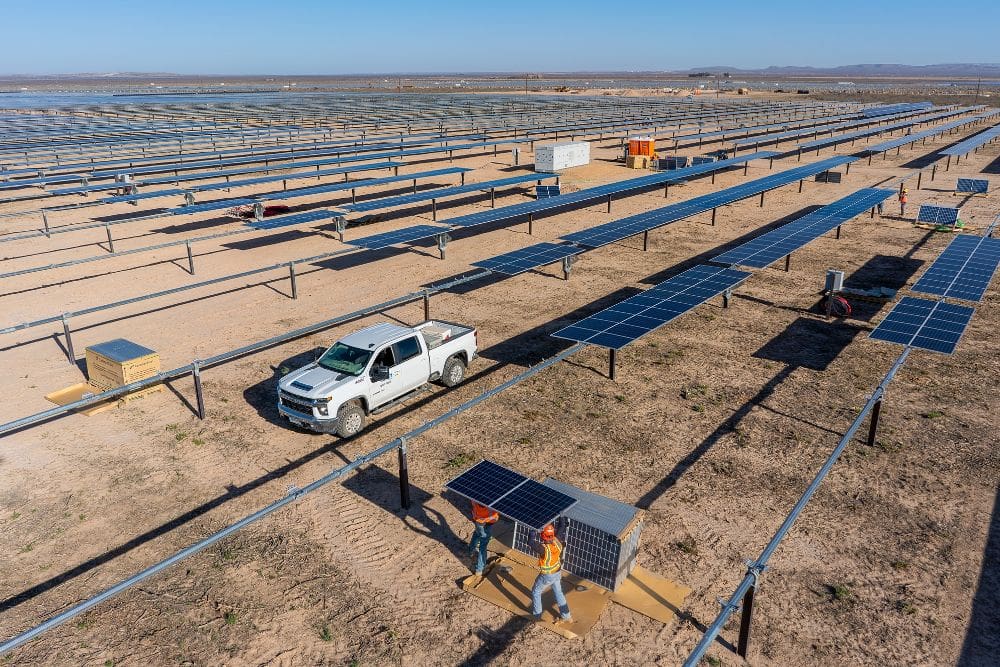 A truck is parked in the middle of an array of solar panels.